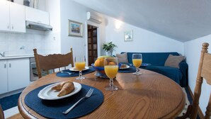 A dining table with a plate of croissants, glasses of orange juice, and a bowl of fruit. - Cozy Stay Apartments (Dubrovnik)