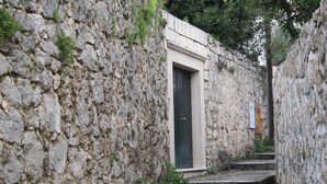 A narrow stone corridor with a door and steps leading to a building. - Cozy Stay Apartments (Dubrovnik)