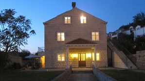 A stone building with a central entrance, a staircase on the right, and a well-maintained lawn. - Cozy Stay Apartments (Dubrovnik)