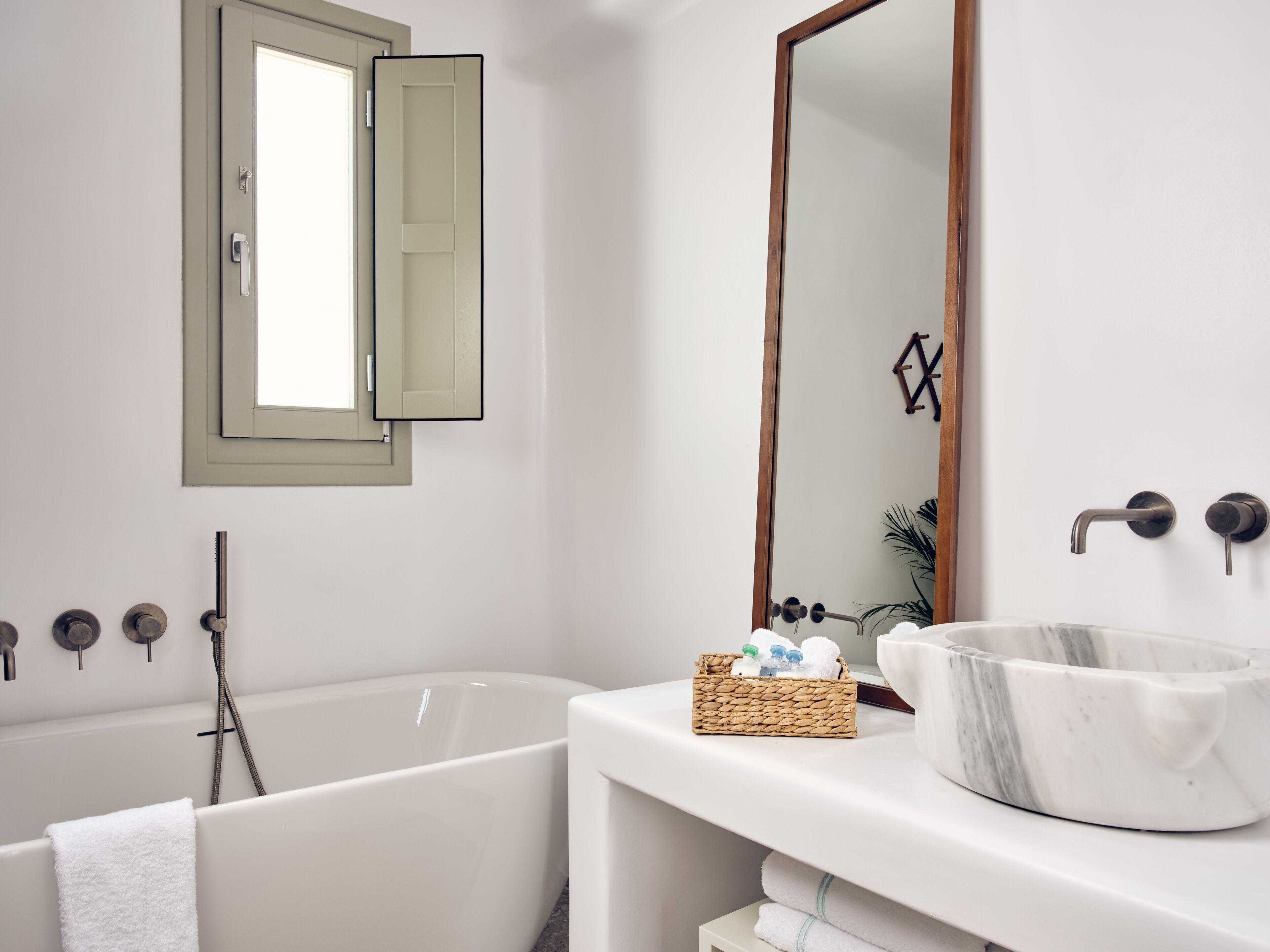 A modern bathroom with a freestanding bathtub, a large mirror, and a marble basin.