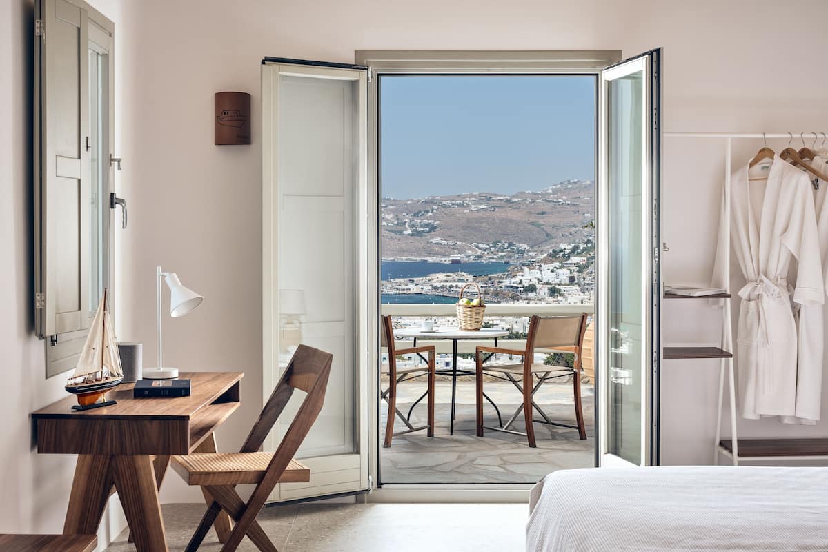 Une chambre d’hôtel avec balcon, une table à manger et une vue sur un paysage côtier.