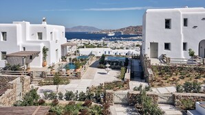 Un pueblo costero con edificios blancos, un cielo azul despejado y vista al mar con barcos.