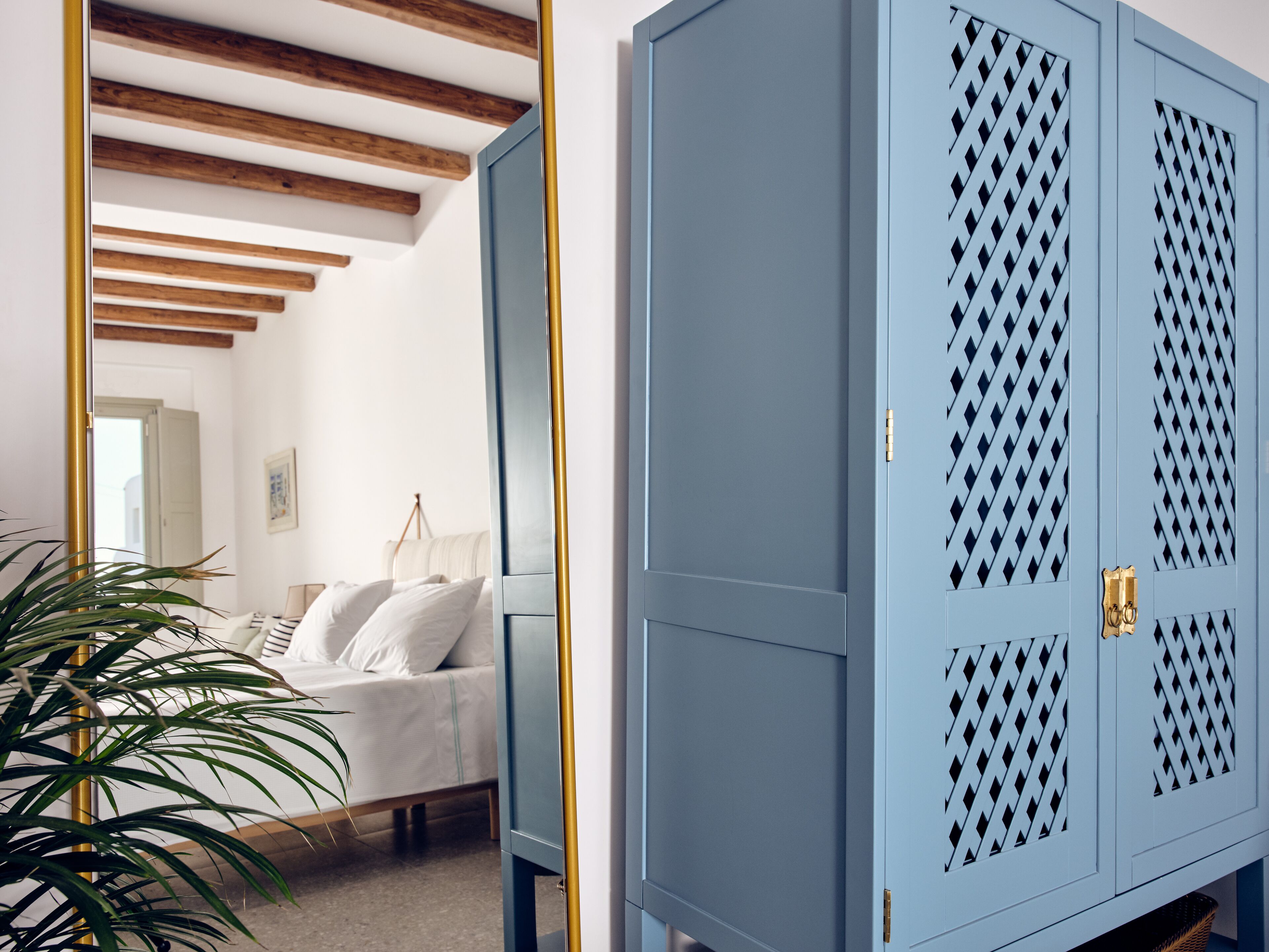 A bedroom with a bed, a wardrobe, and a mirror.