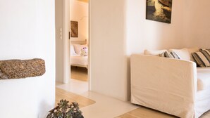 Un salon moderne avec un canapé, une petite table sur laquelle est posée une plante, et un tableau accroché au mur.