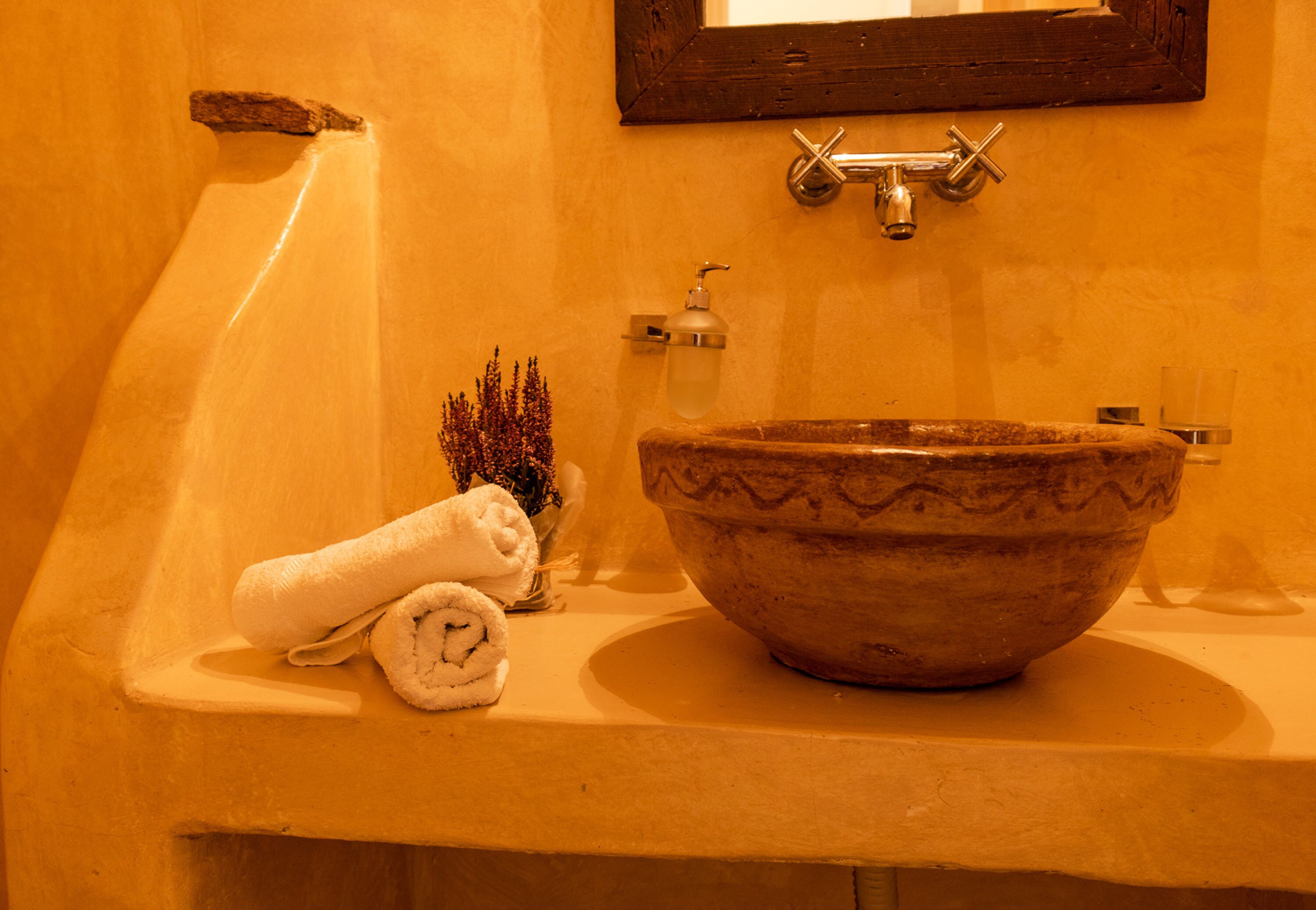 A bathroom with a beige sink, a towel, and a small plant.