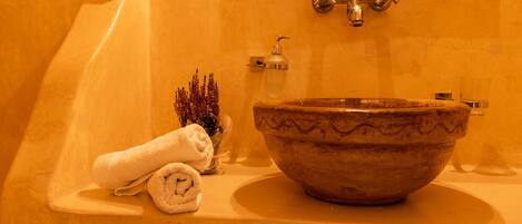 A bathroom with a beige sink, a towel, and a small plant.