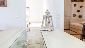 Une pièce avec une table à plateau de verre, une petite lanterne et un lit doté d’une tête de lit en bois.