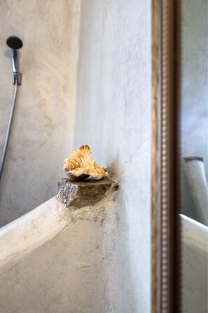 Une coquille sur une étagère en pierre dans une salle de bain.