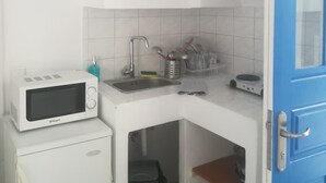 A compact kitchen with a microwave, sink, and storage shelves. - Gorgeous Mykonian Studio DT Ornos (Mykonos)