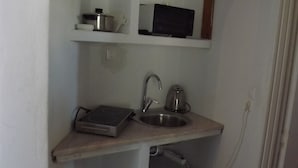 A compact kitchen with a microwave, kettle, and a small stove on a wooden countertop. - Cycladic Studio - 4People DT Ornos (Mykonos)