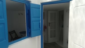 Ein Zimmer mit einer weißen Tür und blauen Verzierungen, einem kleinen Tisch und einem Stuhl.