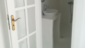 Ein helles Badezimmer mit Tür, Waschbecken und Dusche.