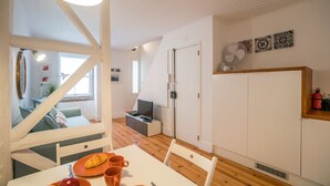 A modern kitchen with white cabinets, a dining table with orange plates and cups, and a staircase leading to a living area.