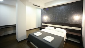 A modern hotel room with a large bed, a dark textured wall, and a built-in shelf. - West Tower Hotel (Kutaisi)