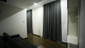 A modern living room with a sofa, a small table, and a built-in TV shelf. - West Tower Hotel (Kutaisi)
