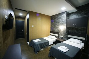 A hotel room with two single beds, a TV mounted on the wall, and a wooden accent wall. - West Tower Hotel (Kutaisi)