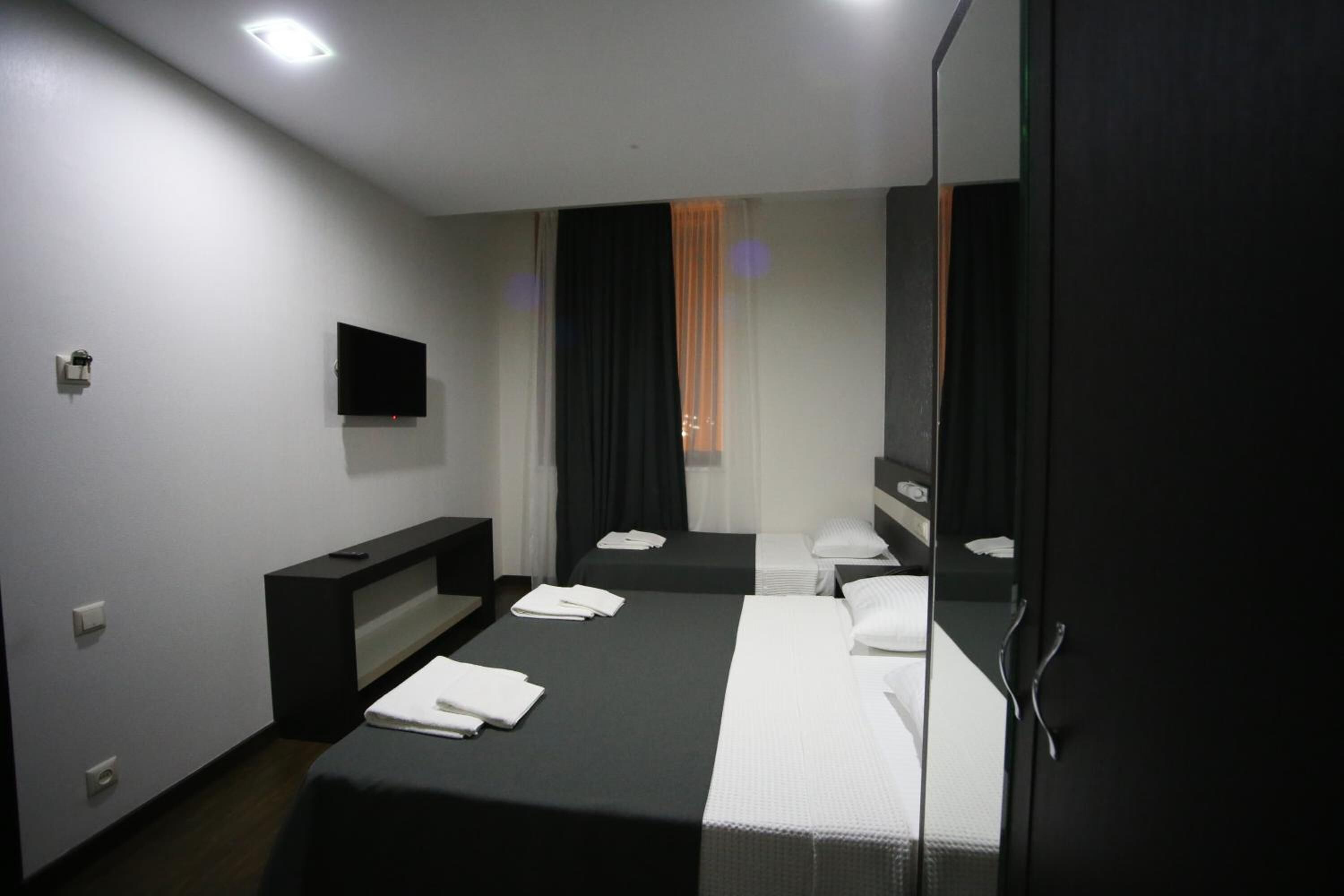 Una habitación de hotel con cama, televisión, escritorio y espejo.