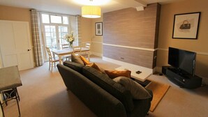 Een moderne woonkamer met een bank, een eettafel en een televisie.