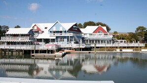 Il s’agit d’une propriété située au bord de l’eau, comprenant plusieurs bâtiments, dont une grande maison avec un toit rouge et un bâtiment plus petit avec un toit bleu.