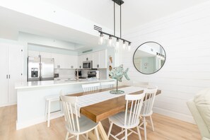 Une cuisine moderne avec des meubles blancs, des appareils en acier inoxydable et un îlot central doté de sièges.