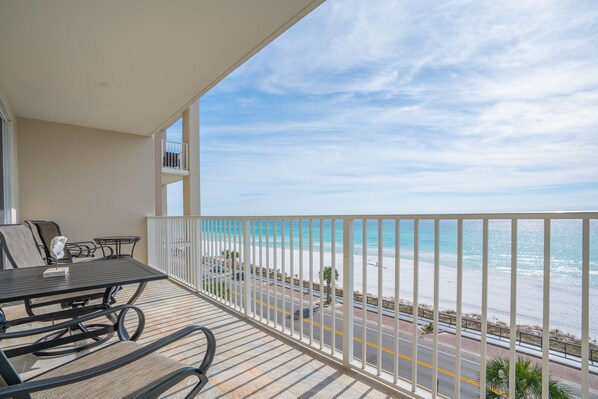 Un balcon donnant sur la plage, une table avec des chaises et une rambarde.