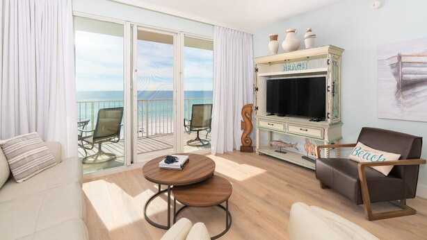 Un balcón amplio con vistas al mar, un rincón acogedor con una mesa redonda y un televisor antiguo sobre un mueble.