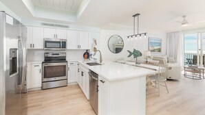 Una cocina moderna con armarios blancos, electrodomésticos de acero inoxidable y una isla central.