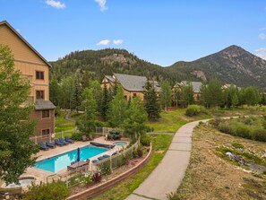 A residential area with a swimming pool, lounge chairs, and a walking path.