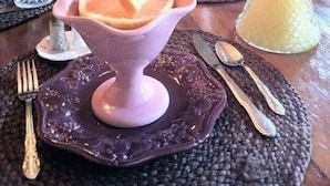 Ein Esstisch gedeckt mit einer rosa Dessertschale, einem Zitronenlimonadenkrug und verschiedenen Gläsern.