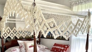 Ein Himmelbett mit Baldachin, floralem Bettzeug und einem roten Kissen mit Text.