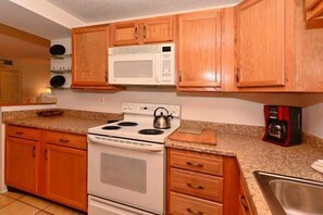 Kitchen area with a stove, microwave, and coffee maker, offering ample storage and a convenient sink.