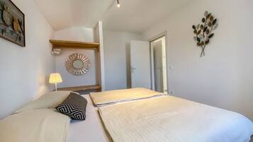 A bedroom with a large bed, a bedside lamp, a decorative mirror, and a wall-mounted artwork.