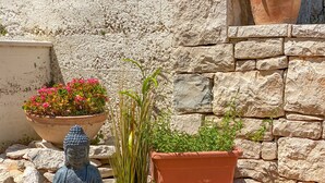A Buddha statue, a large flower pot, and a terracotta pot on a wooden deck against a stone wall. - Eco apartments Sunshine - Dance Lovers for 4 (Lumbarda)