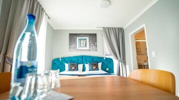 A room with a bed, a table with glasses, and a bottle.