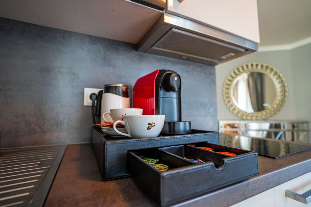 Une cuisine moderne équipée d’une machine à café, de tasses et d’un plateau à thé.
