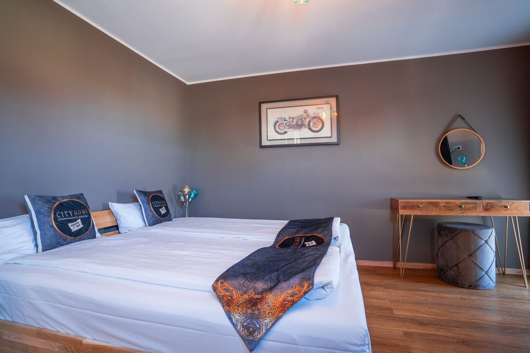 A bedroom with a bed, pillows, a desk, and a chair.