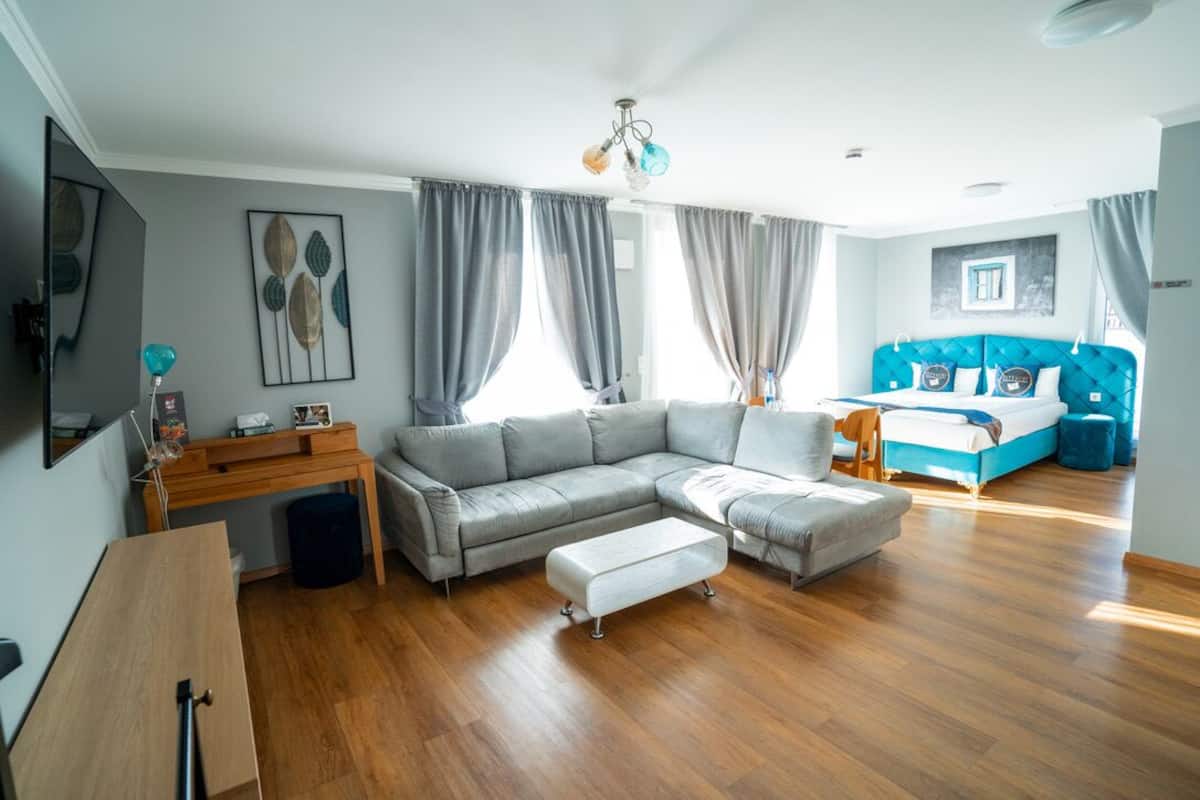 A modern living room with a grey sectional sofa, a wooden desk, and a blue accent wall.