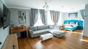 A modern living room with a grey sectional sofa, a wooden desk, and a blue accent wall.