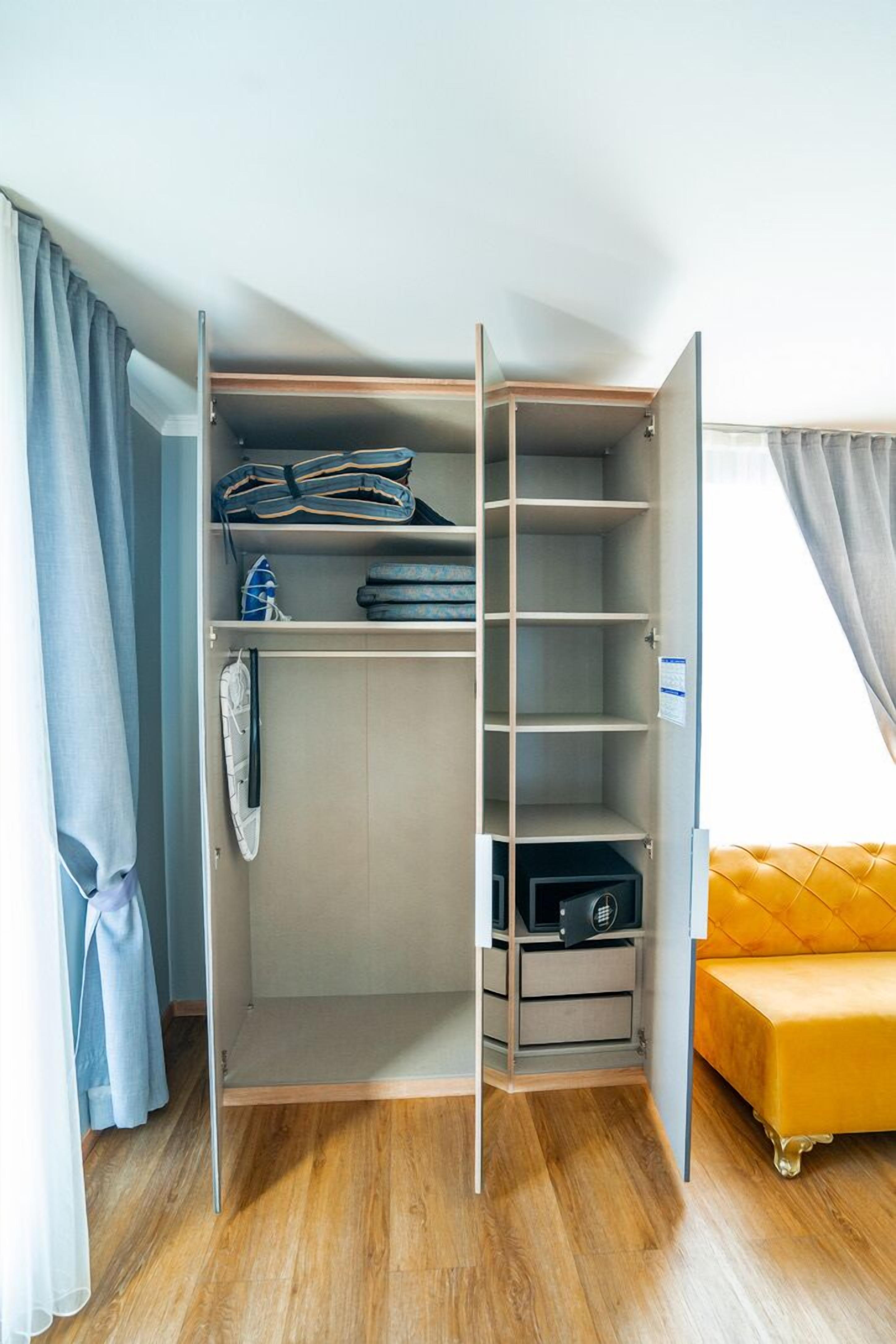 A walk-in closet with open doors, featuring shelves, drawers, and hanging space.