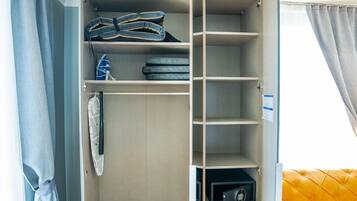 A walk-in closet with open doors, featuring shelves, drawers, and hanging space.