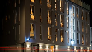 Un edificio moderno de varios pisos, con amplias ventanas y un letrero que indica que es una pensión.