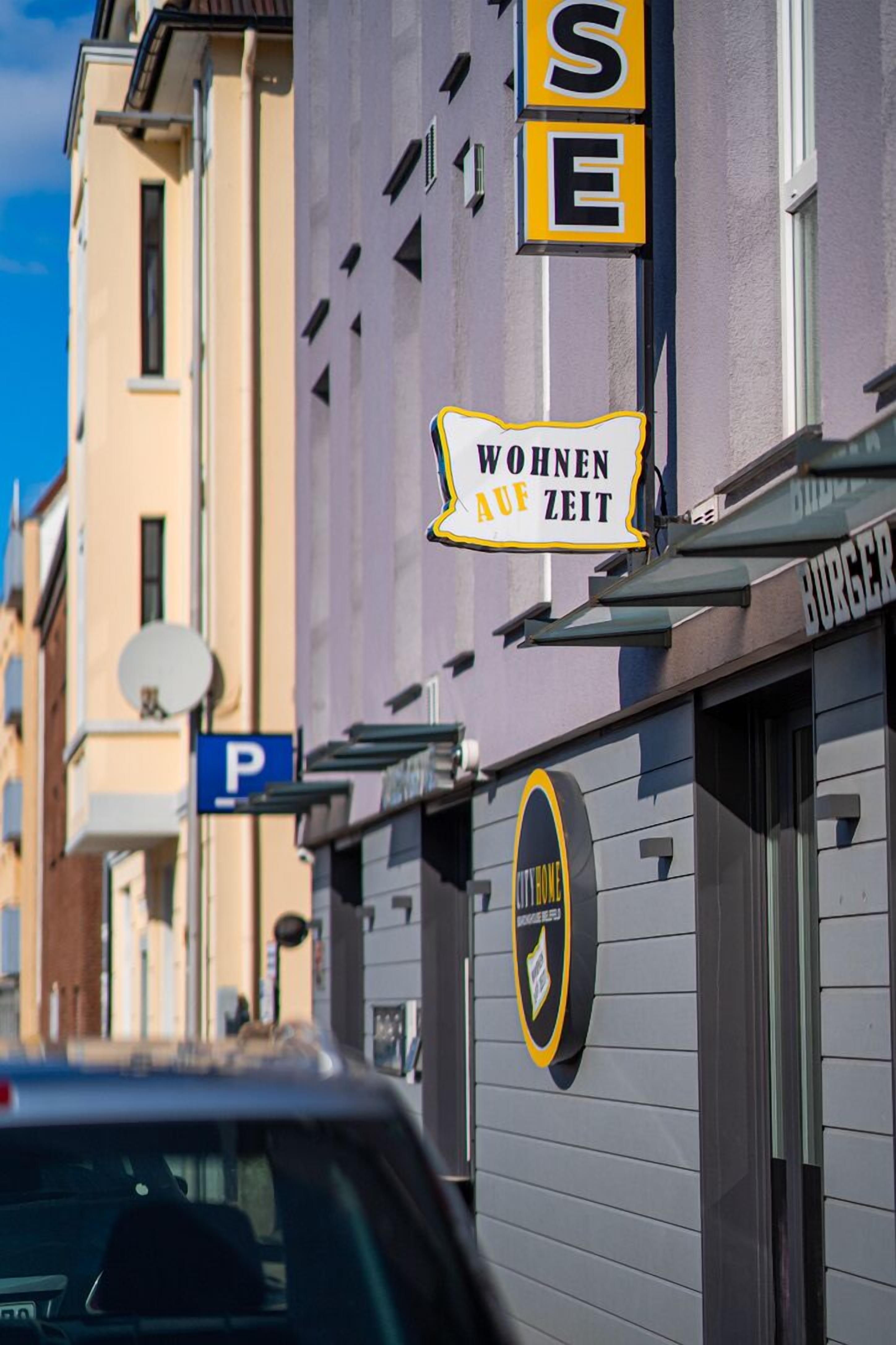 A building with a sign that reads "Wohnen auf Zeit" and a parking sign.