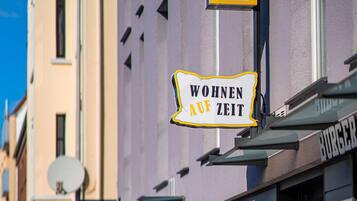 A building with a sign that reads "Wohnen auf Zeit" and a parking sign.