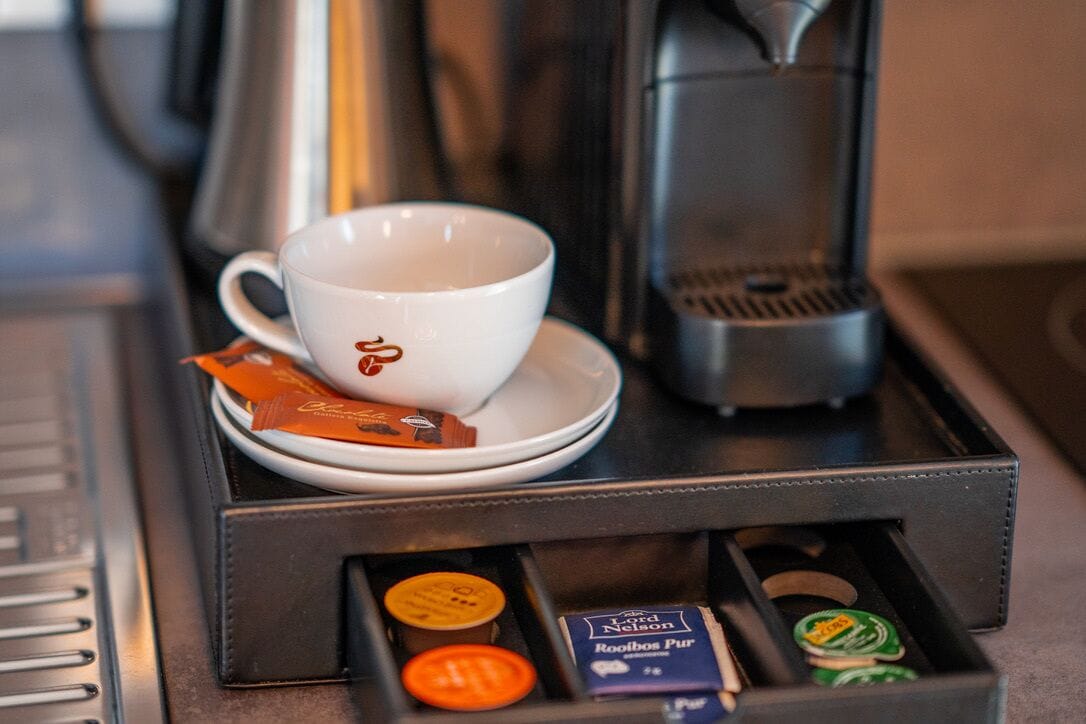 Une machine à café avec une tasse et une soucoupe, ainsi qu’un compartiment pour les dosettes de café.