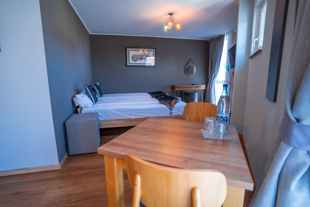 Una habitación pequeña con cama, una mesita y una silla.