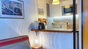 A compact living space with a kitchenette, a sofa, and a painting on the wall.