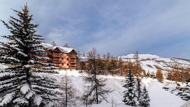 A lodge with a snow-covered landscape, surrounded by trees and mountains.