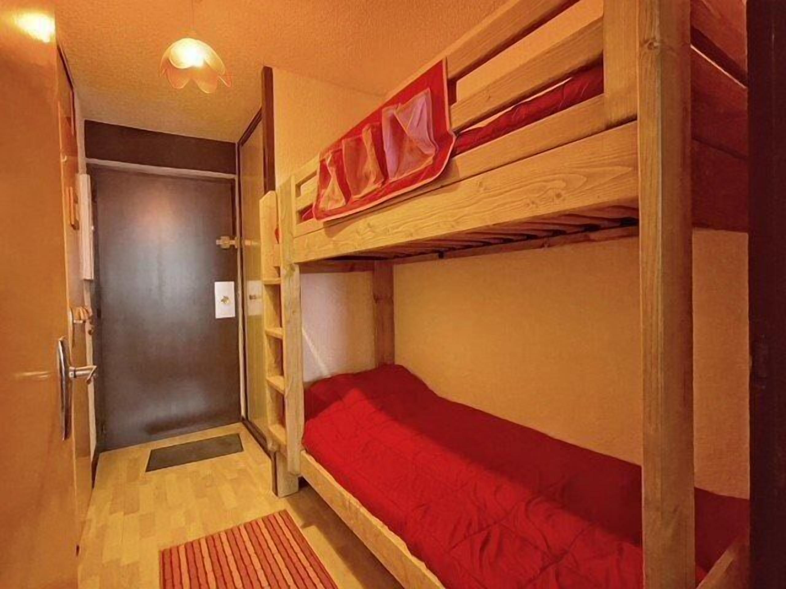A bunk bed room with a wooden door and a small window.