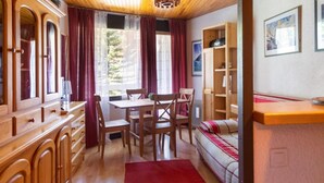 A cozy room with a wooden dining table, chairs, a sofa, and a bookshelf.