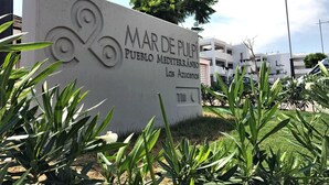 A sign for 'Mare de Pulpí Pueblo Mediterráneo Las Azucenas' with a modern design and a clear view of the surrounding area including buildings and greenery. - Casa Alexandra 4-person penthouse on the seafront in Mar de Pulpi. (Pulpí)